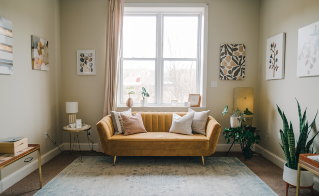 Warm, welcoming therapy room with a sofa beside a sunlit window